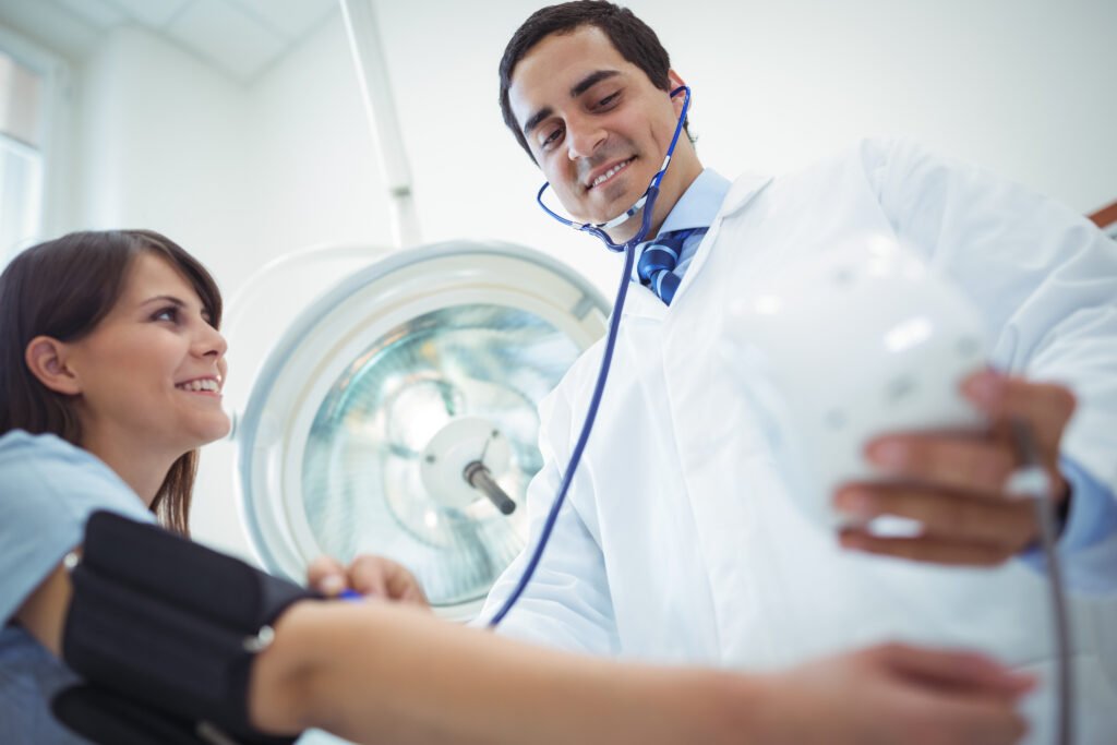 A doctor checks a patient’s blood pressure with a smile.
