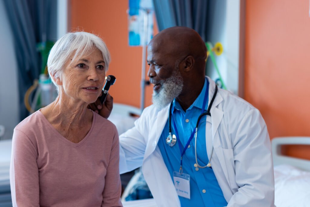 A doctor examines an elderly woman’s ear in a medical setting.