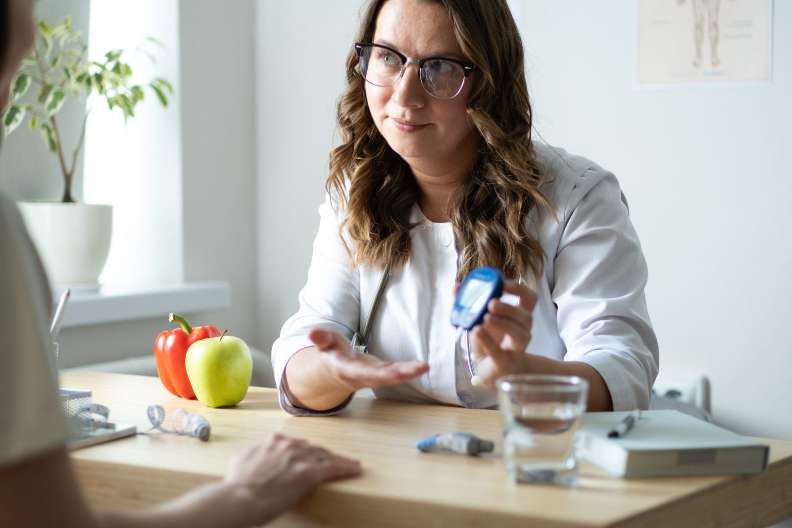 The doctor shows the glucometer to the patient. A female endocrinologist is seeing a patient in her office on the topic of measuring blood sugar levels. High quality photo